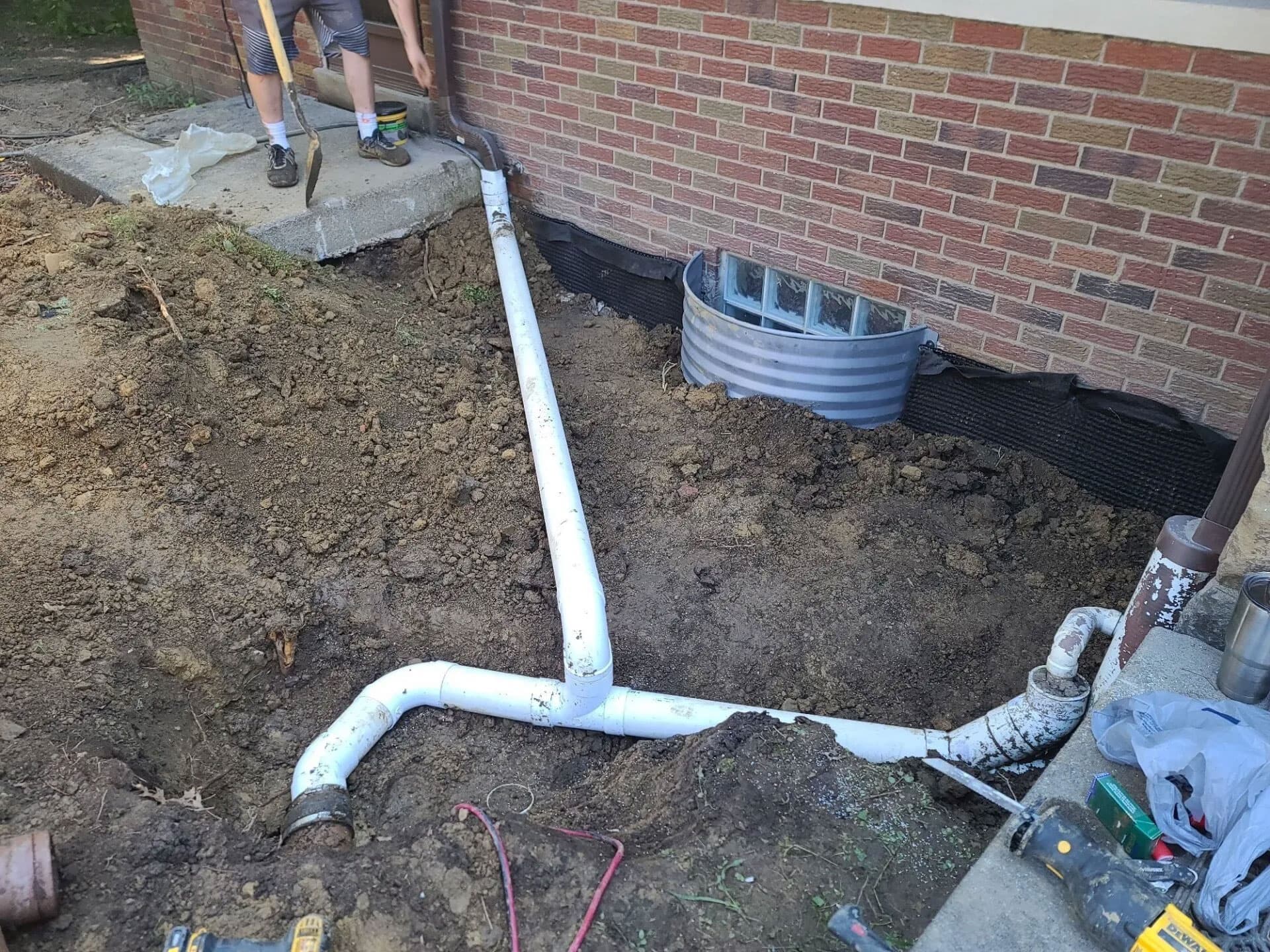 PVC downspout drainage piping being routed away from a brick home foundation