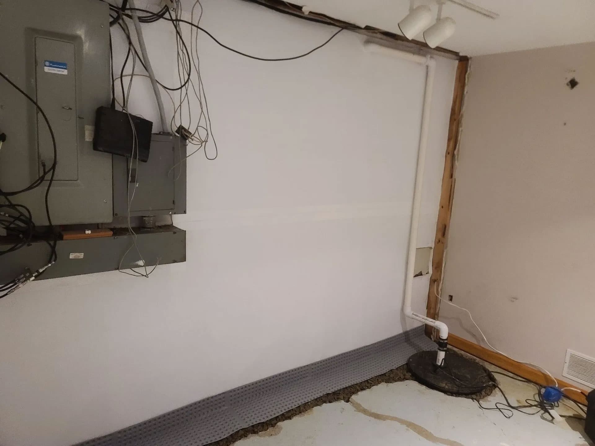 Sump pump with discharge pipe tied into a dimpled membrane and fresh concrete drainage channel